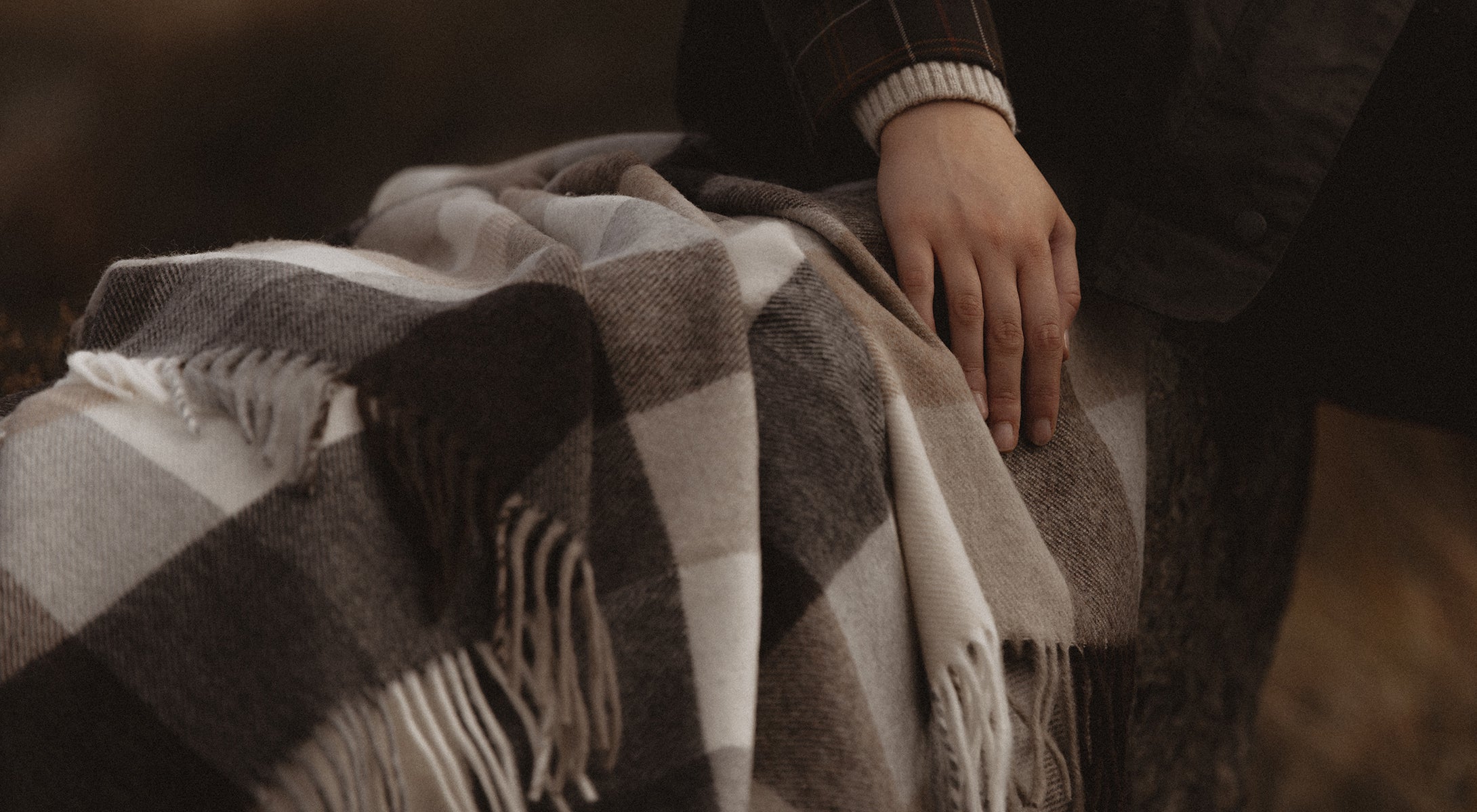 Person wrapped in a plaid blanket with a blurred background
