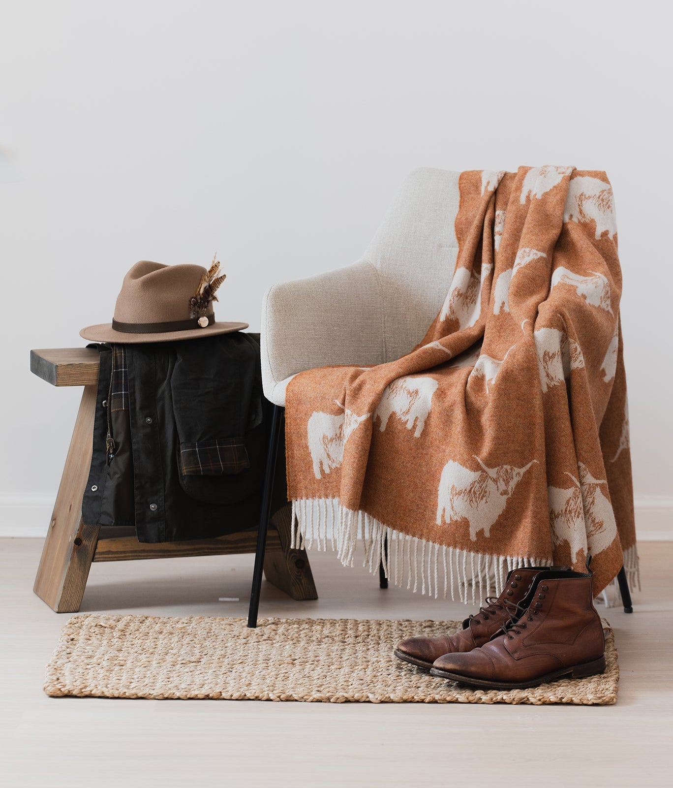 Highland Cow rust remony nature throw on cream chair with hat and jacket on a stool