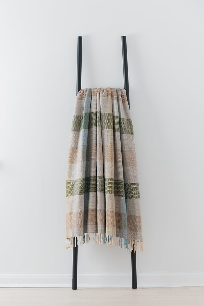 Remony patchwork hayloft throw - blanket draped over a black metal ladder against a white background