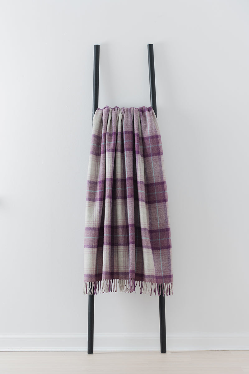Remony lindores grape throw - Plaid scarf draped over a black metal ladder on a white background