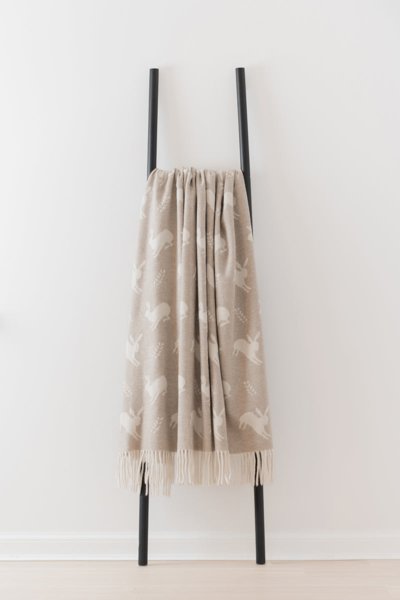 Remony nature hare fawn - Beige patterned blanket draped over a black metal ladder on a white background