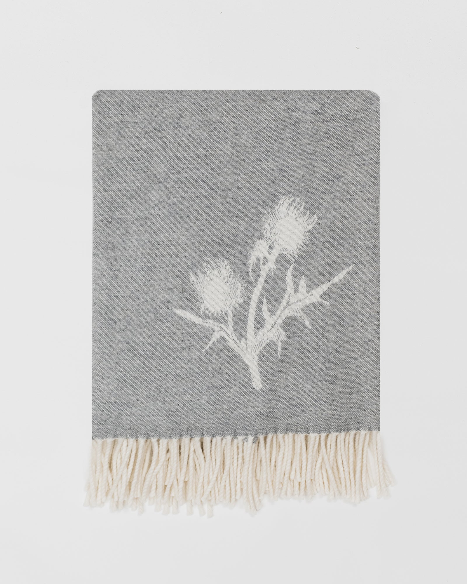 Remony nature thistle and bee grey blanket with white floral design and fringes on a light grey background
