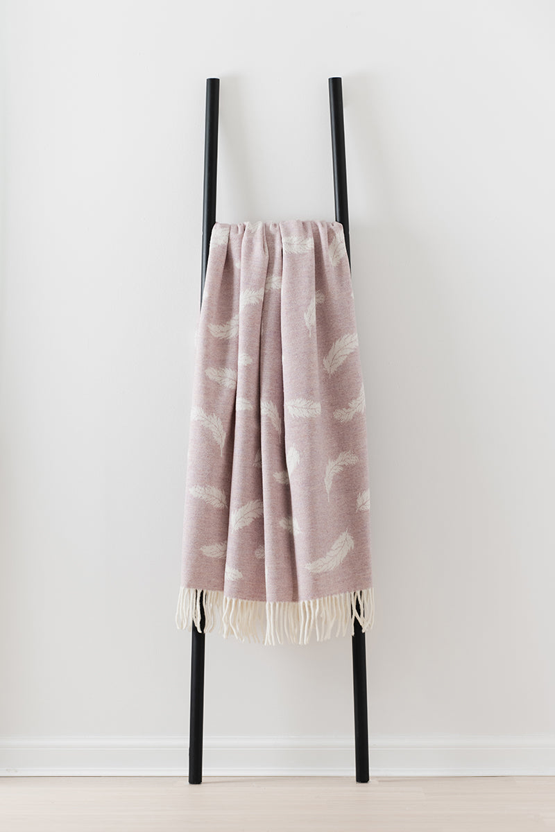 Remony Nature Feather Blossom throw - Pink blanket with white patterns draped over a black ladder on a white background