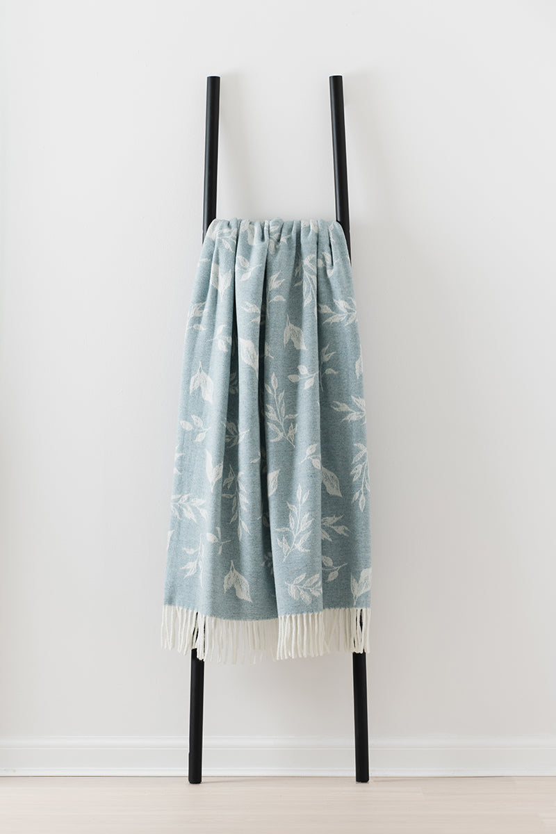 Remony Nature leaf topaz throw with white patterns on a black rack against a white background