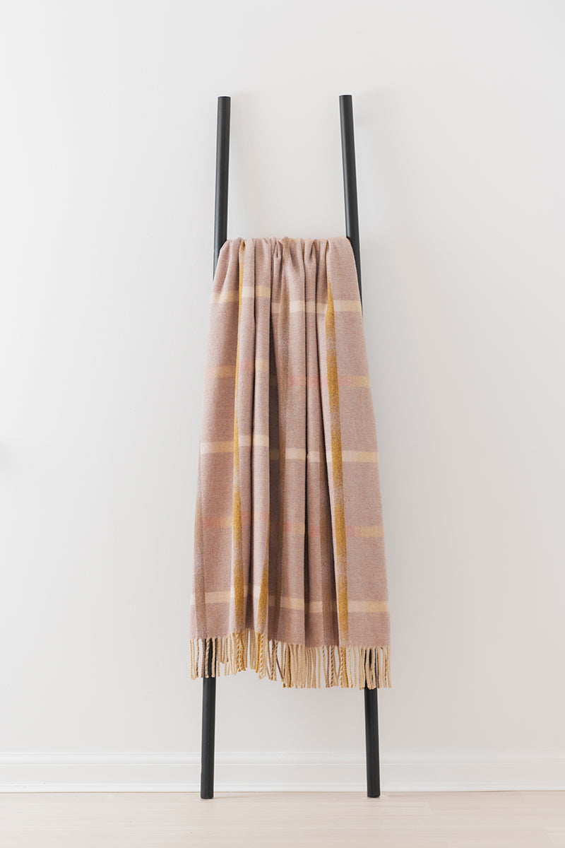 Remony maree sepia throw - check blanket draped over a black metal ladder against a white background