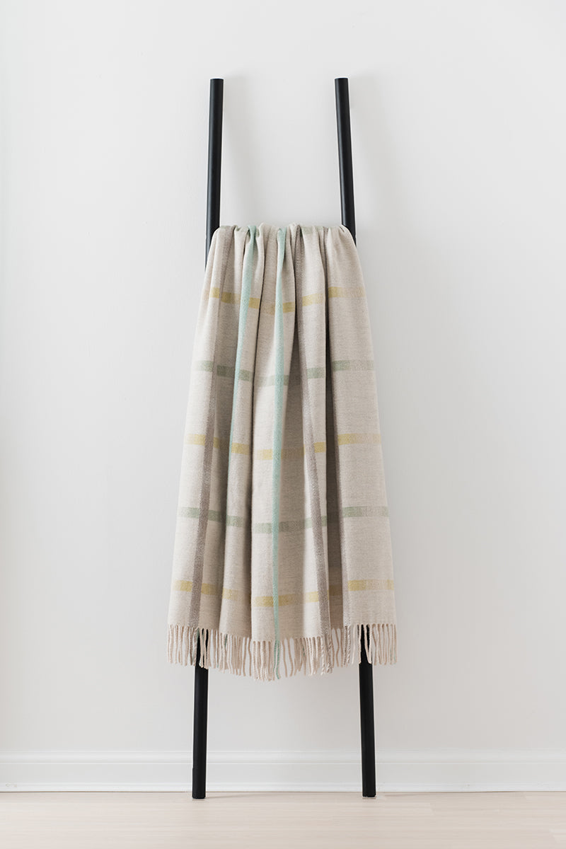 Remony maree feather throw - check blanket draped over a black metal ladder on a white background