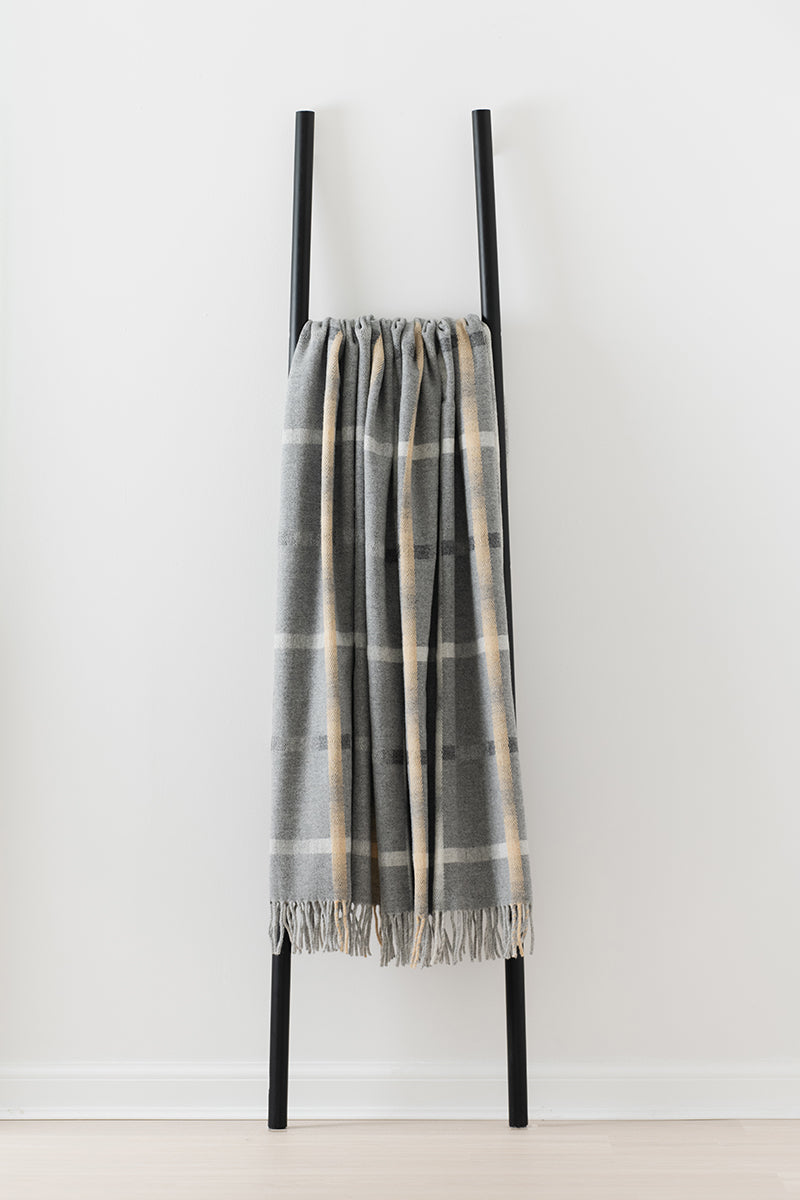 Remony maree mist throw - check blanket draped over a black ladder against a white background