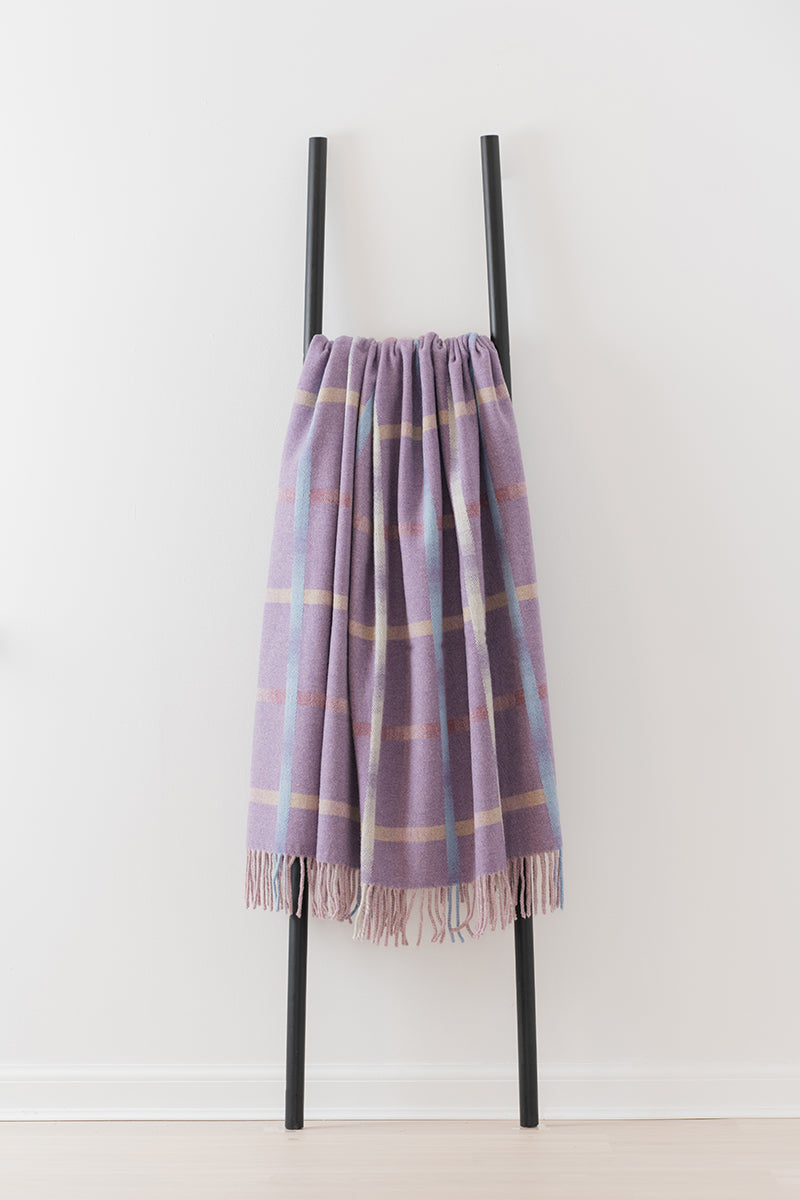 Remony maree amethyst throw - check blanket draped over a black metal ladder on a white background