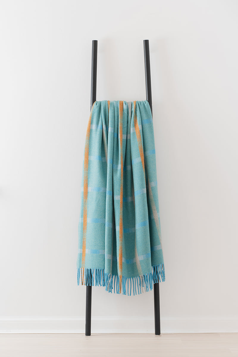 Remony maree jade throw - check blanket draped over a black metal ladder on a white background