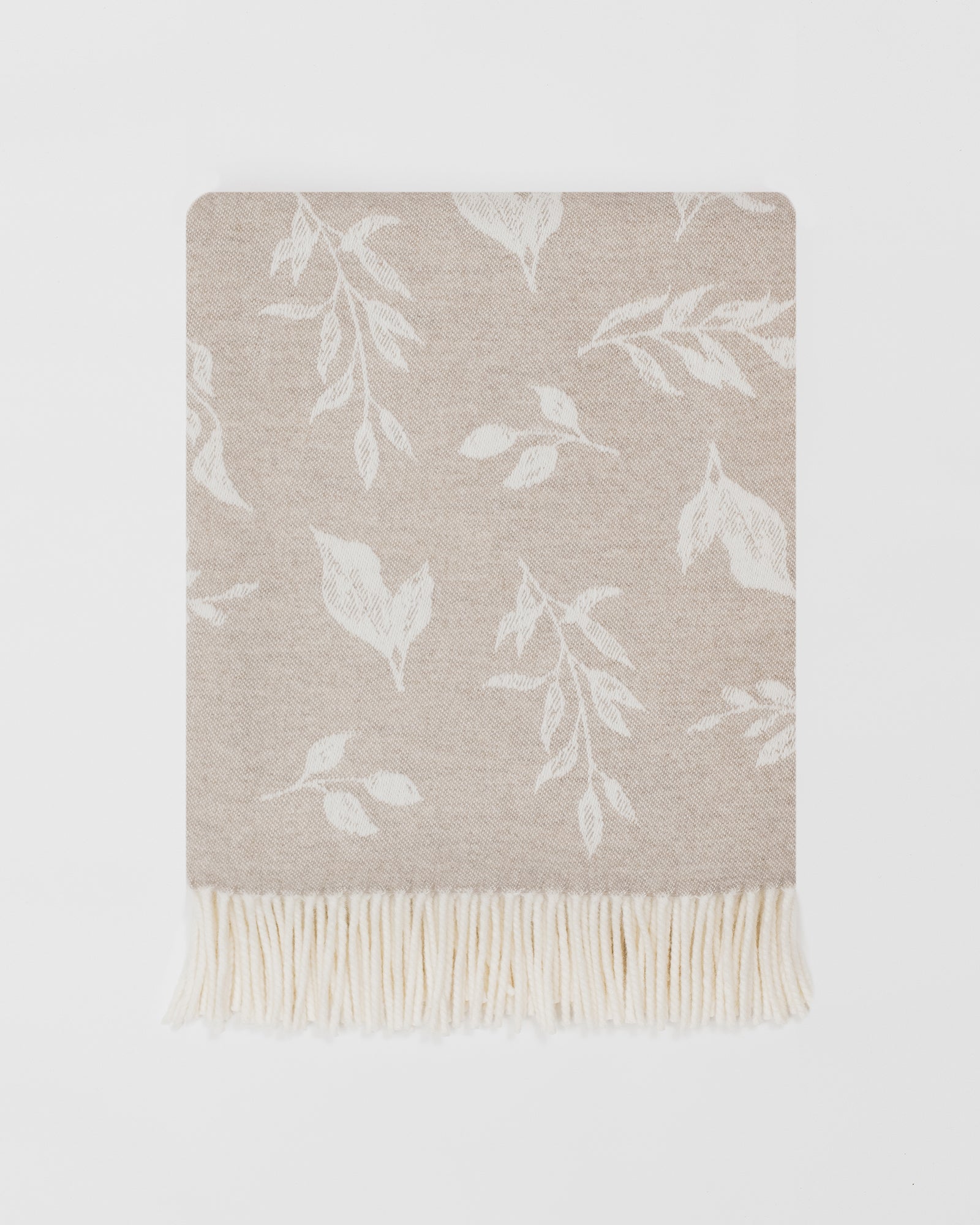 Remony nature leaf oatmeal throw - Beige throw blanket with white leaf pattern on a light gray background