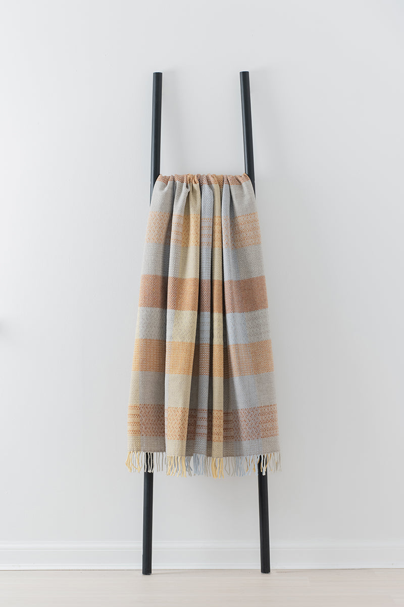 Remony Patchwork sunshine throw - blanket draped over a black metal ladder against a white background