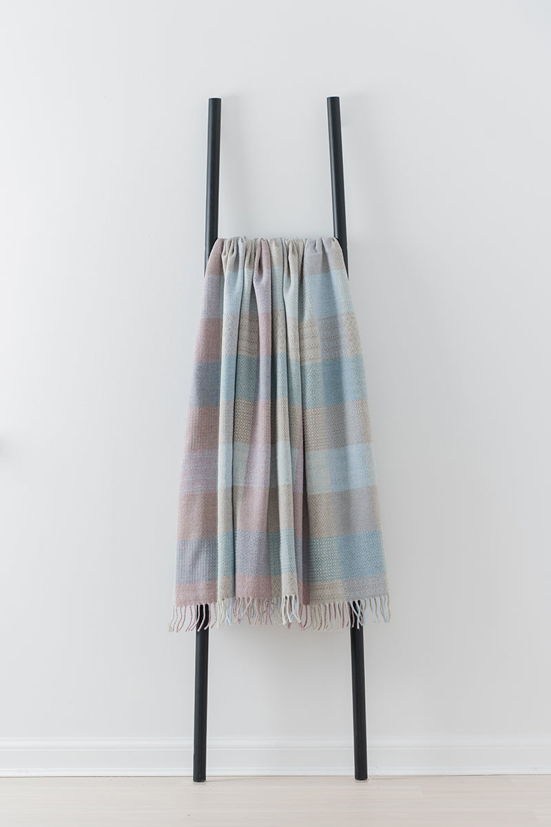 Remony Patchwork sea breeze throw -blanket draped over a black metal ladder on a white background