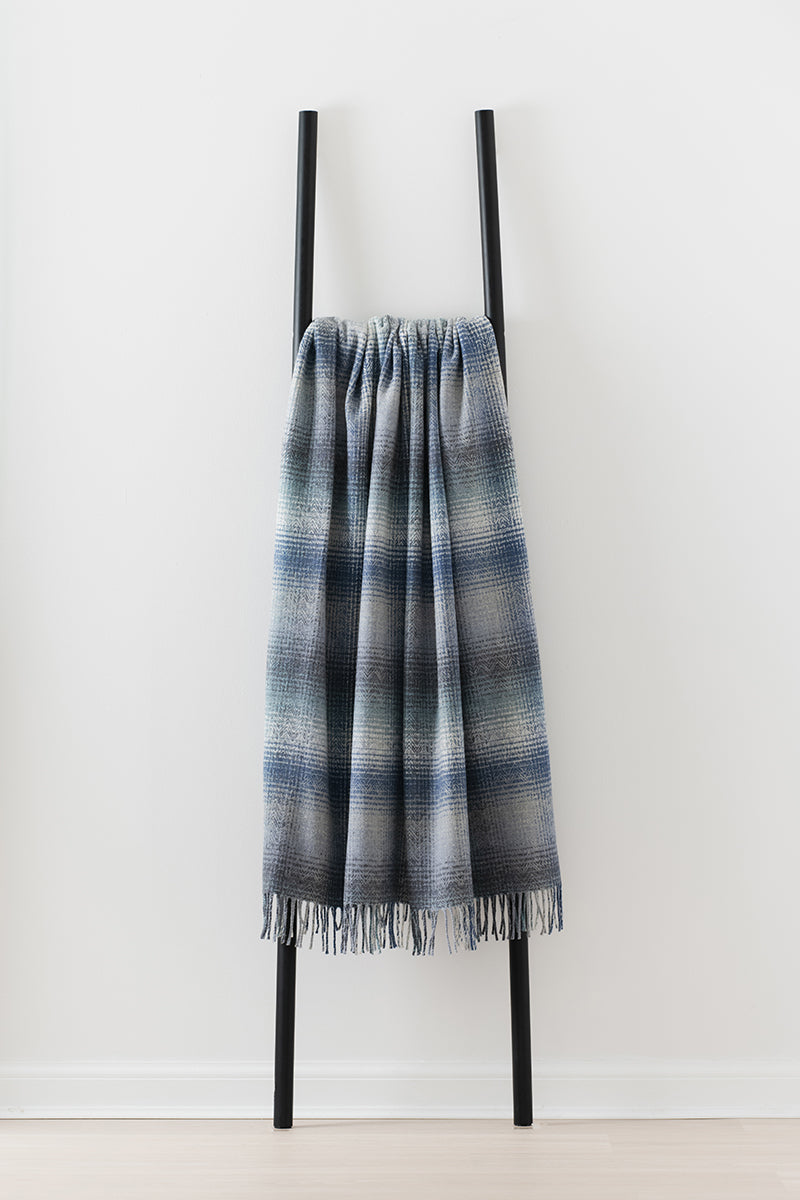 Remony Lunan tidal throw - Blue and grey check blanket draped over a black ladder on a white background