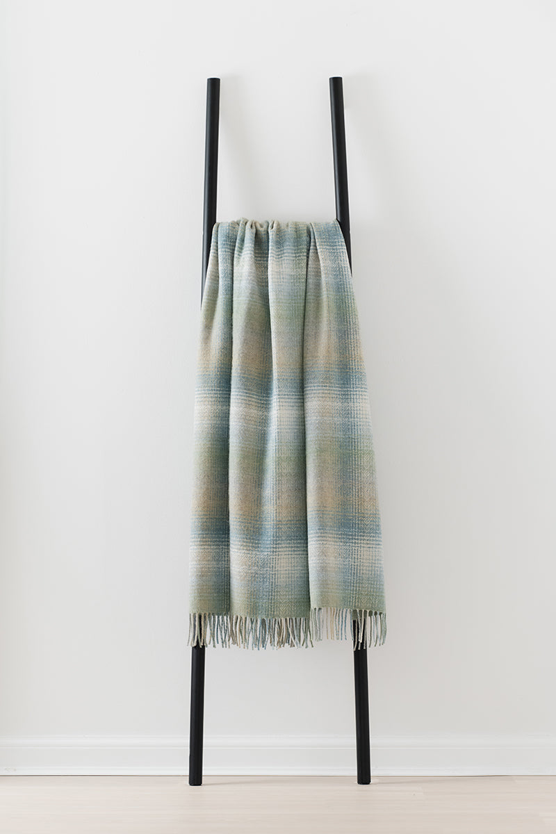 Remony lunan meadow throw - Plaid blanket draped over a black metal rack on a white background