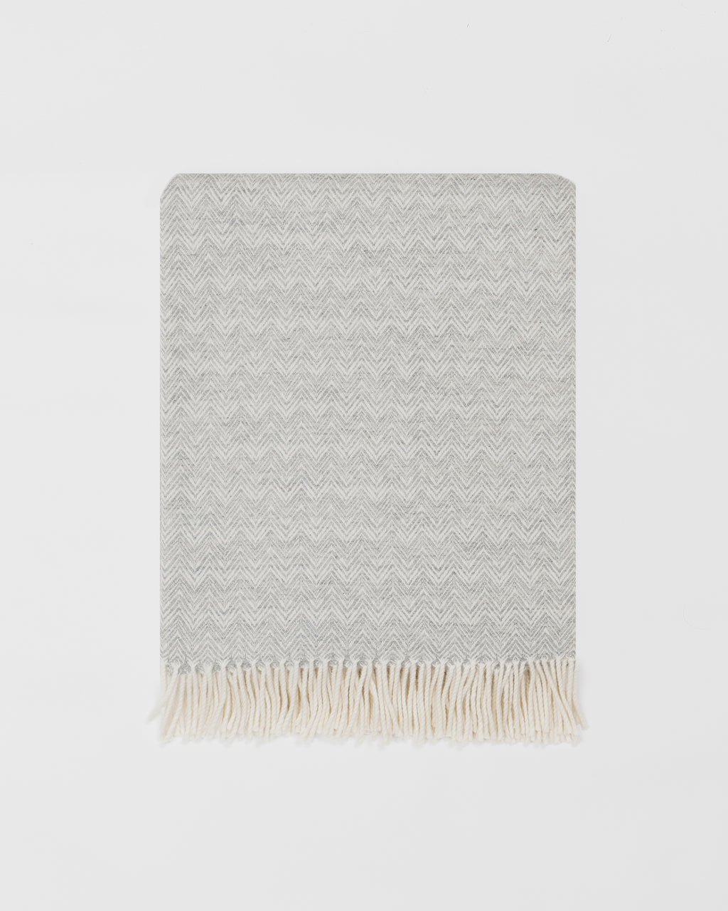 Remony lunan mist throw - Grey woven blanket with white fringe on a light grey background