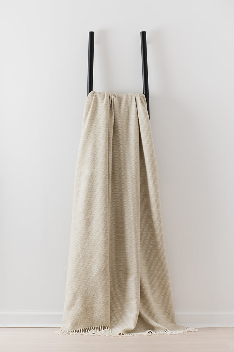 Remony Clova moss large throw - blanket draped over a black rack against a white wall