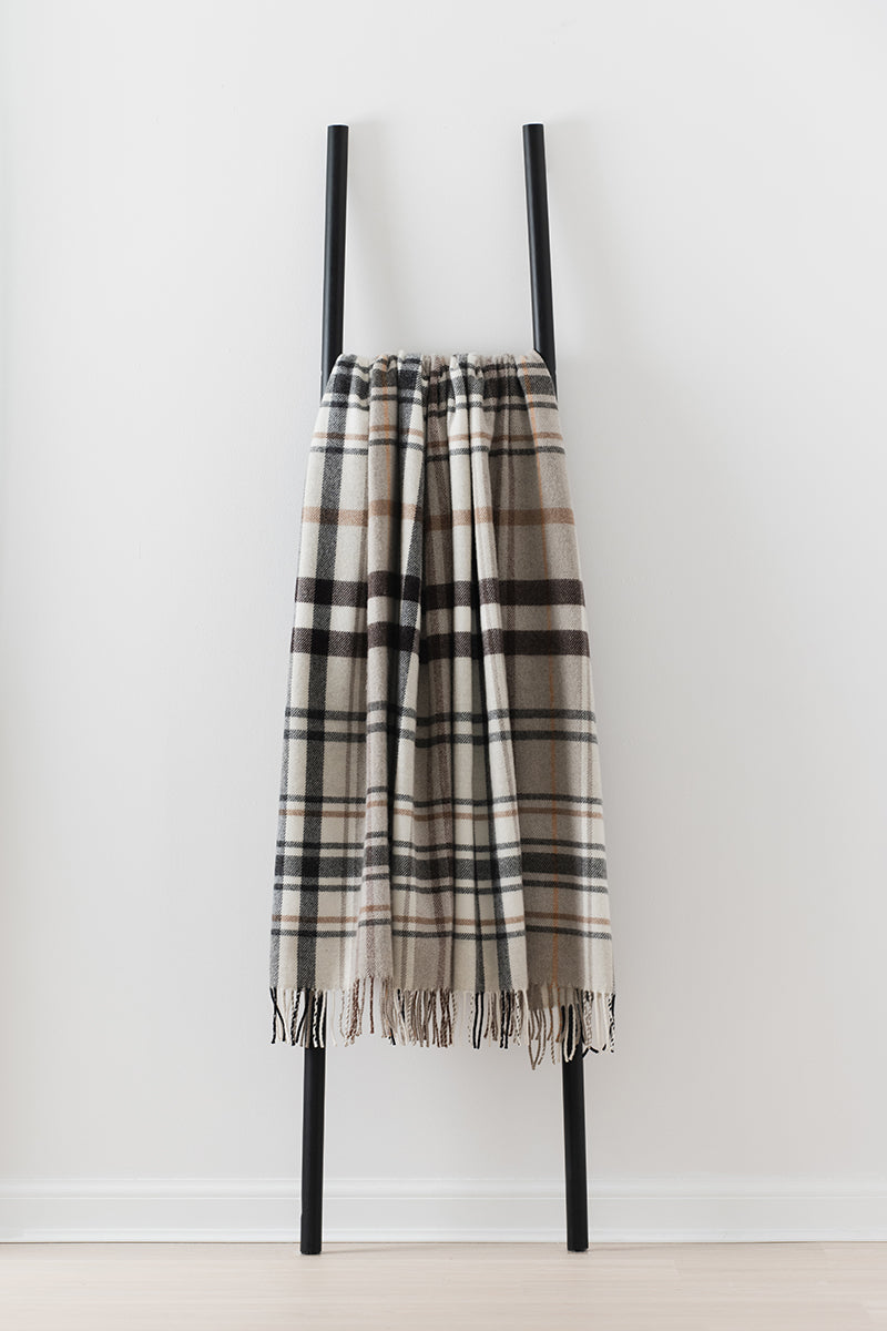 Remony pitnacree stone throw - blanket draped over a black metal ladder on a white background