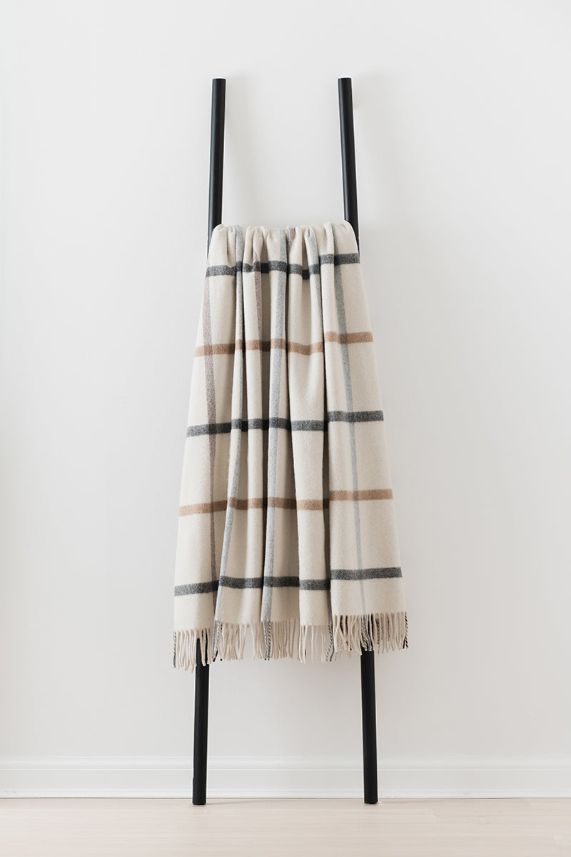 Remony Milton Pebble throw - Plaid blanket draped over a black ladder against a white background