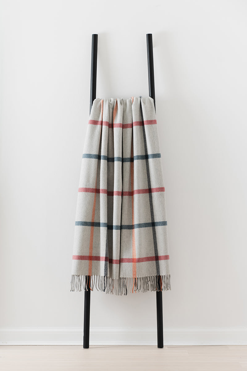 Remony milton melba throw - Plaid blanket with fringe draped over a black ladder on a white background