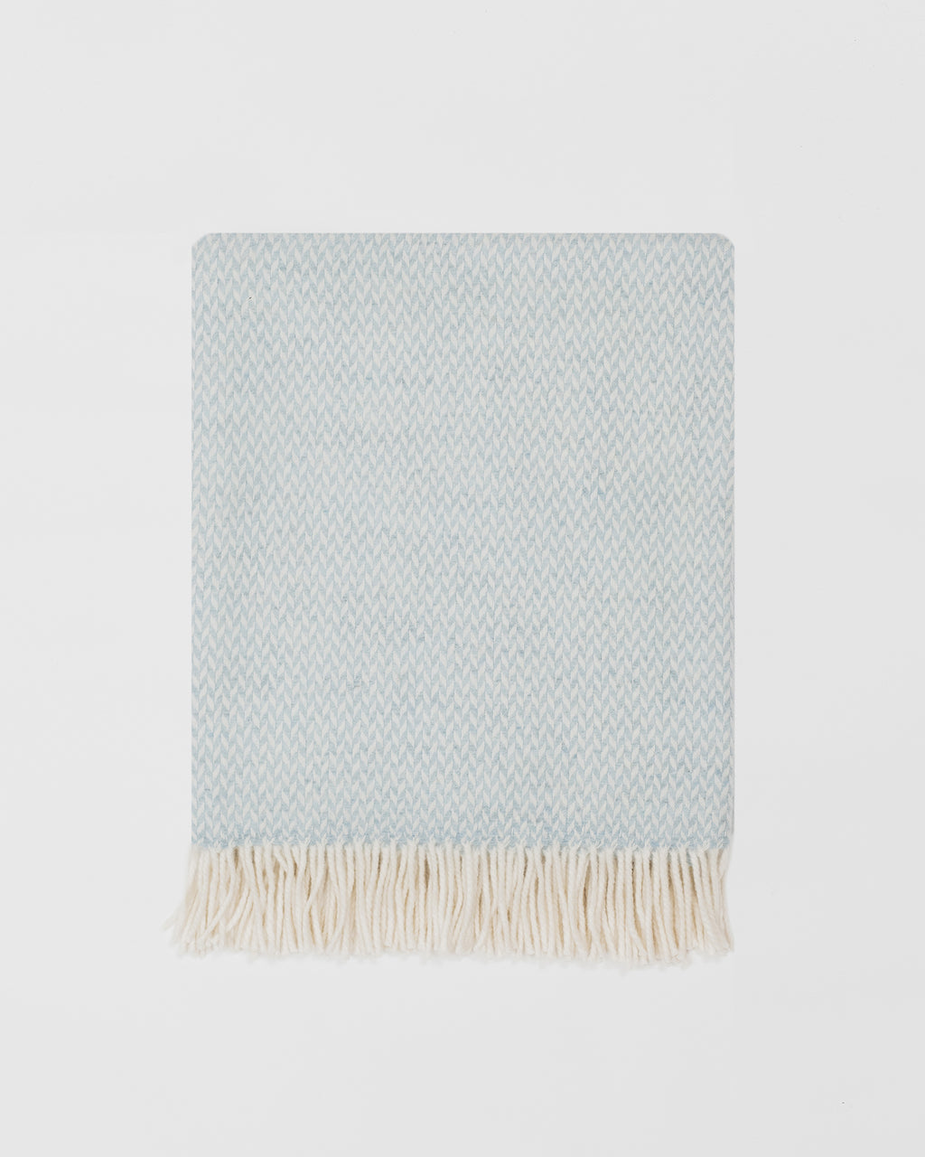 Remony balintyre aquamarine throw - Light blue woven blanket with white fringe on a light gray background