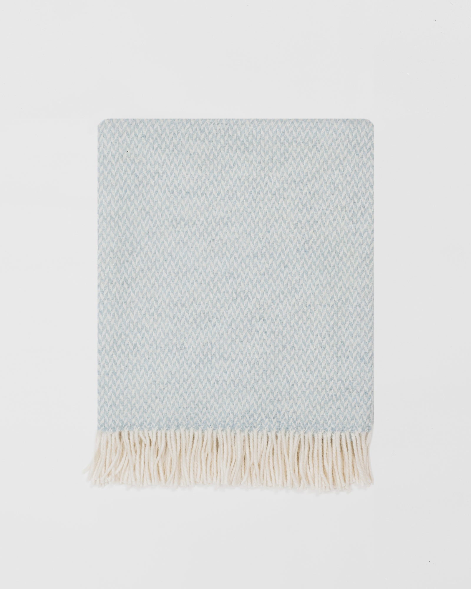 Remony balintyre aquamarine throw - Light blue woven blanket with white fringe on a light gray background
