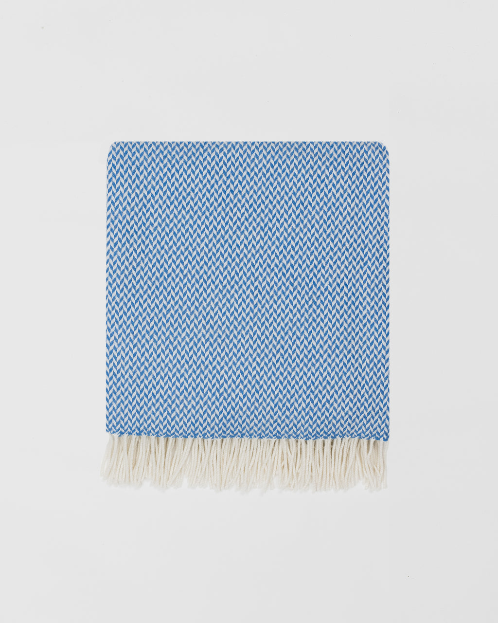 Remony balintyre cornflower throw - Blue and white woven blanket with fringes on a light gray background