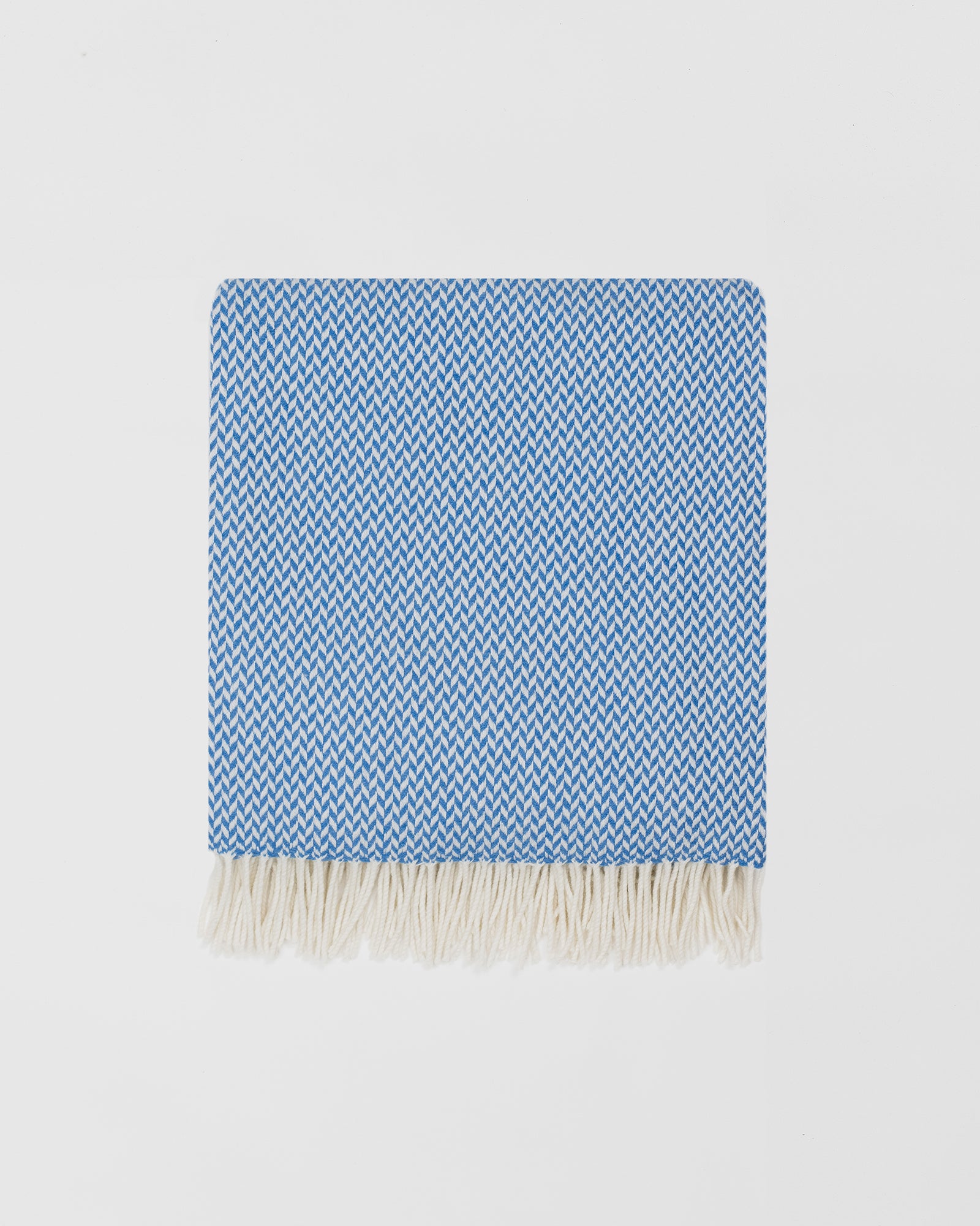 Remony balintyre cornflower throw - Blue and white woven blanket with fringes on a light gray background