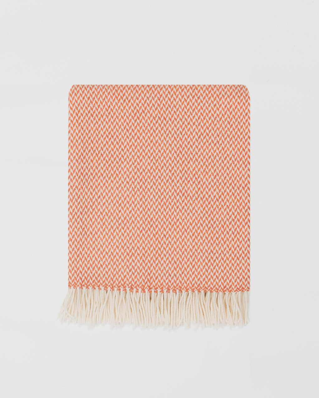 Remony balintyre clementine throw -Orange and white patterned banket with fringes on a light gray background