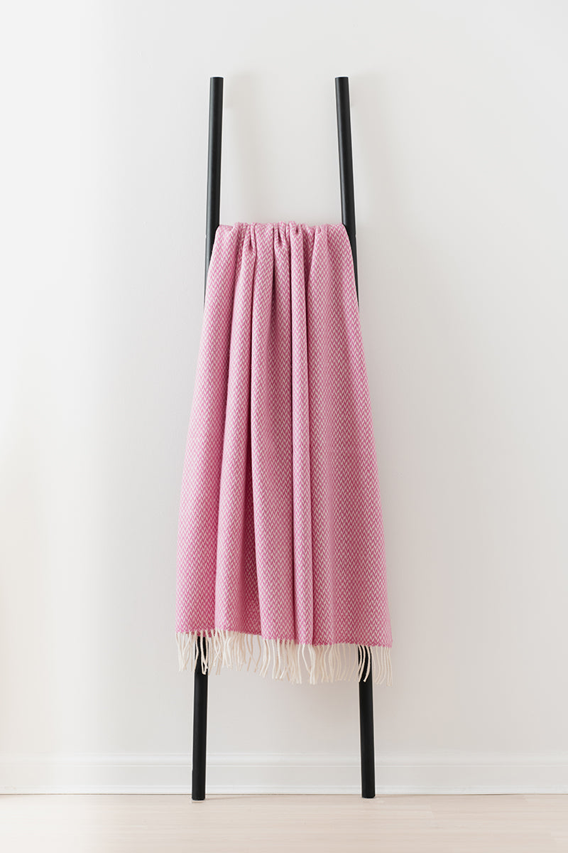 Remony balintyre foxglove throw - Pink woven blanket draped over a black metal ladder on a white background