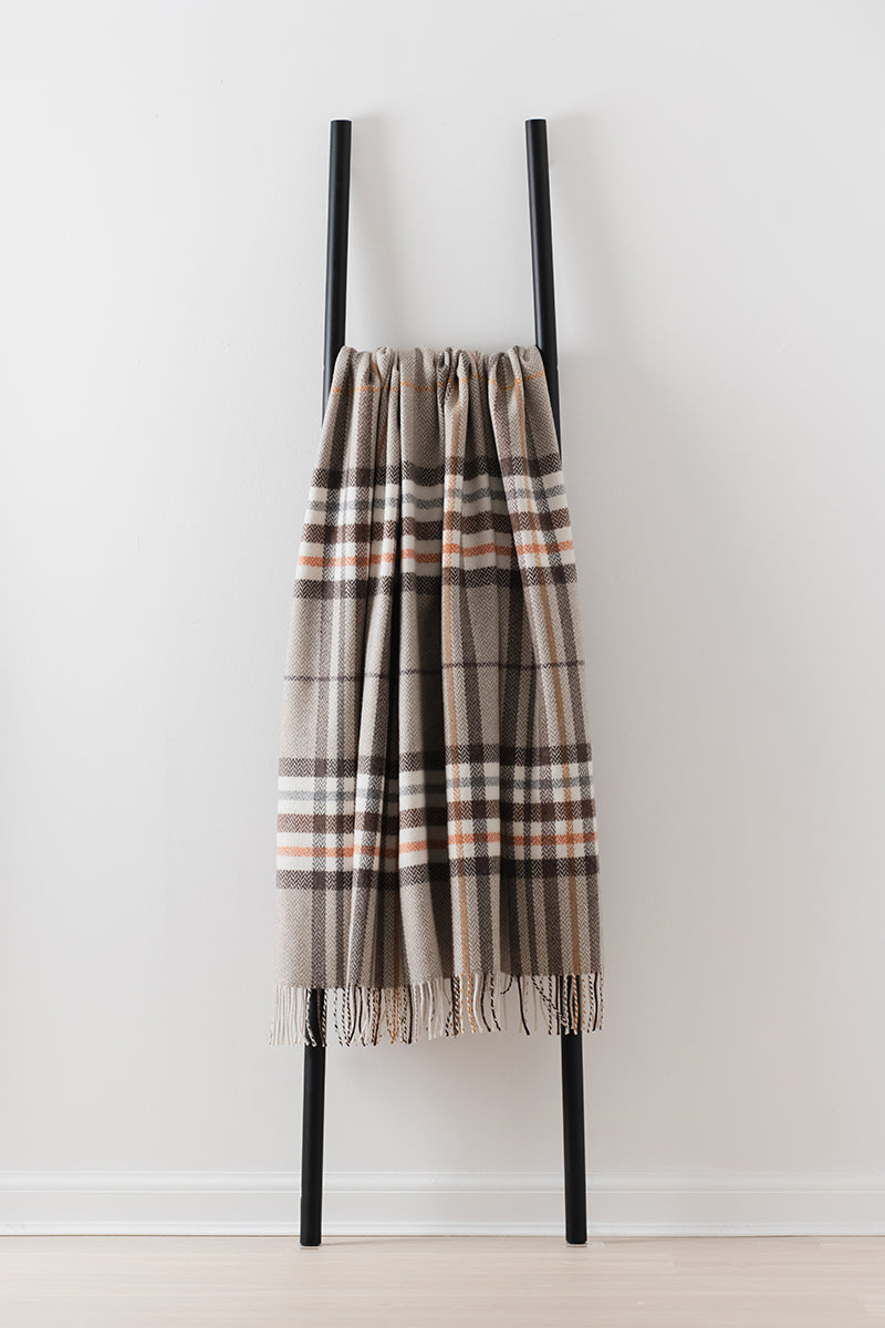Remony moraig bronze throw - Plaid scarf draped over a black metal ladder on a white background