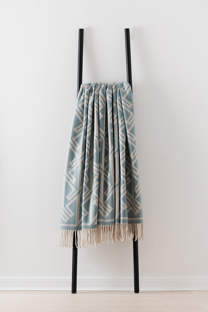 Remony fortriu woad throw - blanket with a geometric pattern on a black rack against a white background