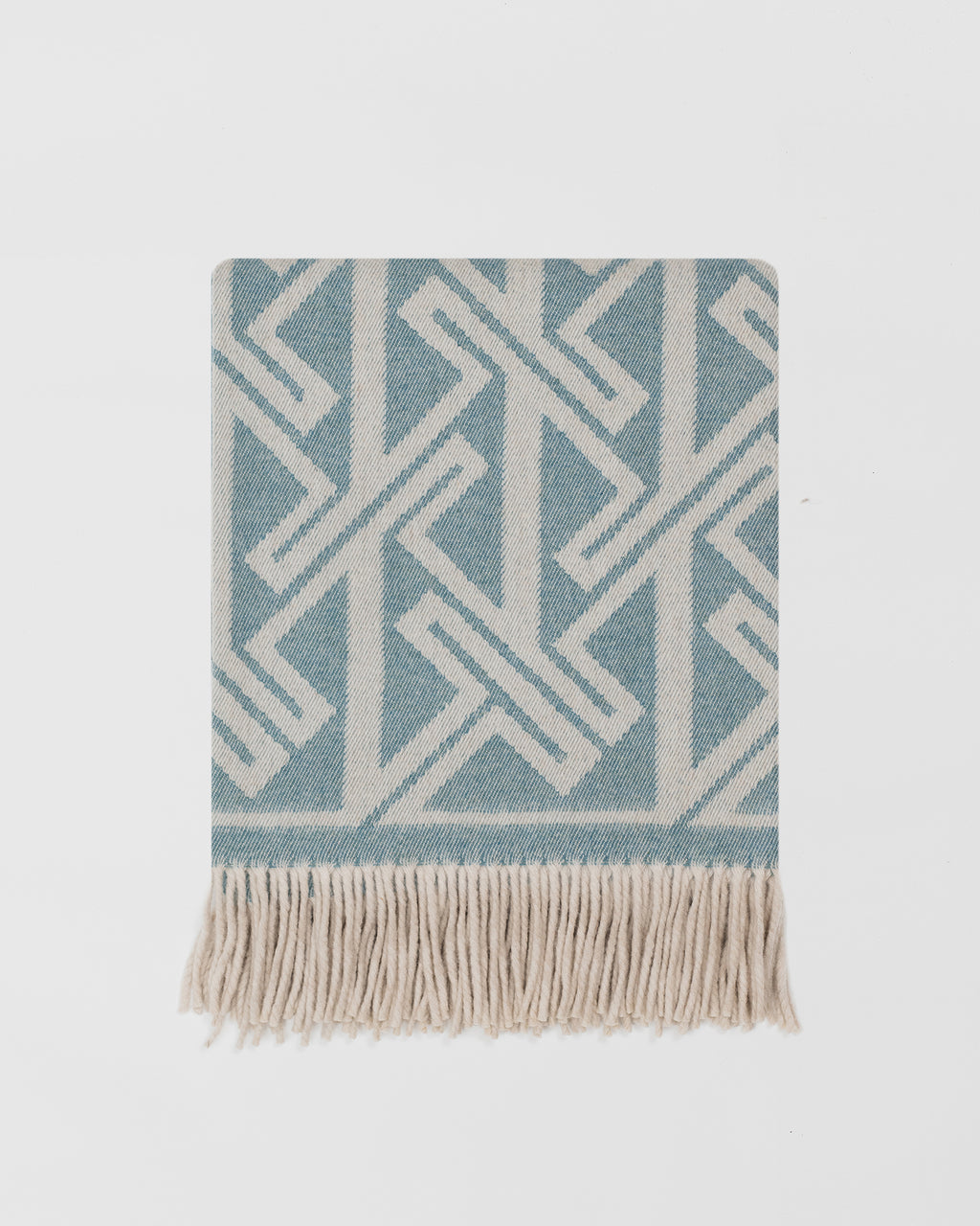 Remony fortriu woad throw - Blue and white geometric patterned throw blanket with fringes on a light grey background