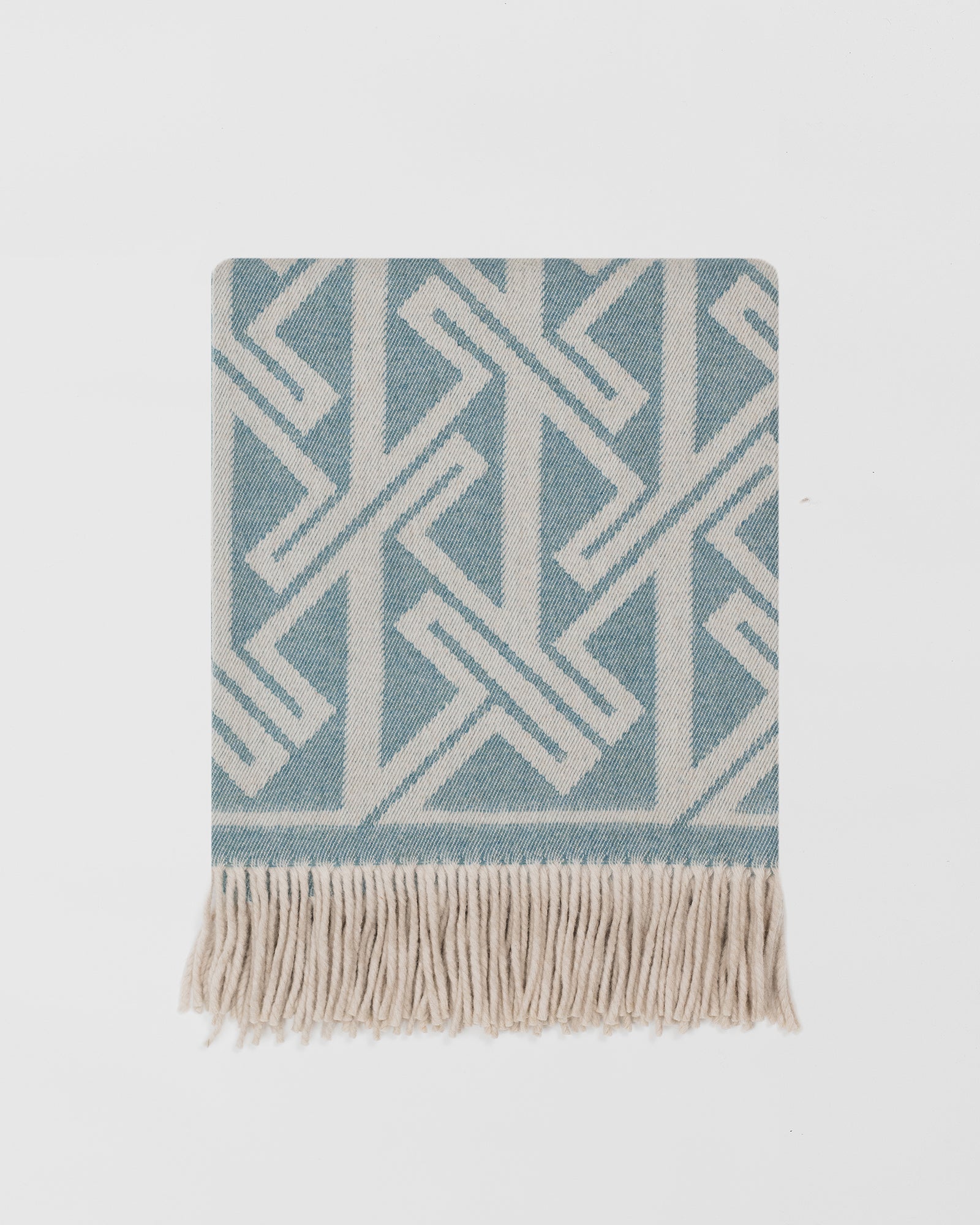 Remony fortriu woad throw - Blue and white geometric patterned throw blanket with fringes on a light grey background