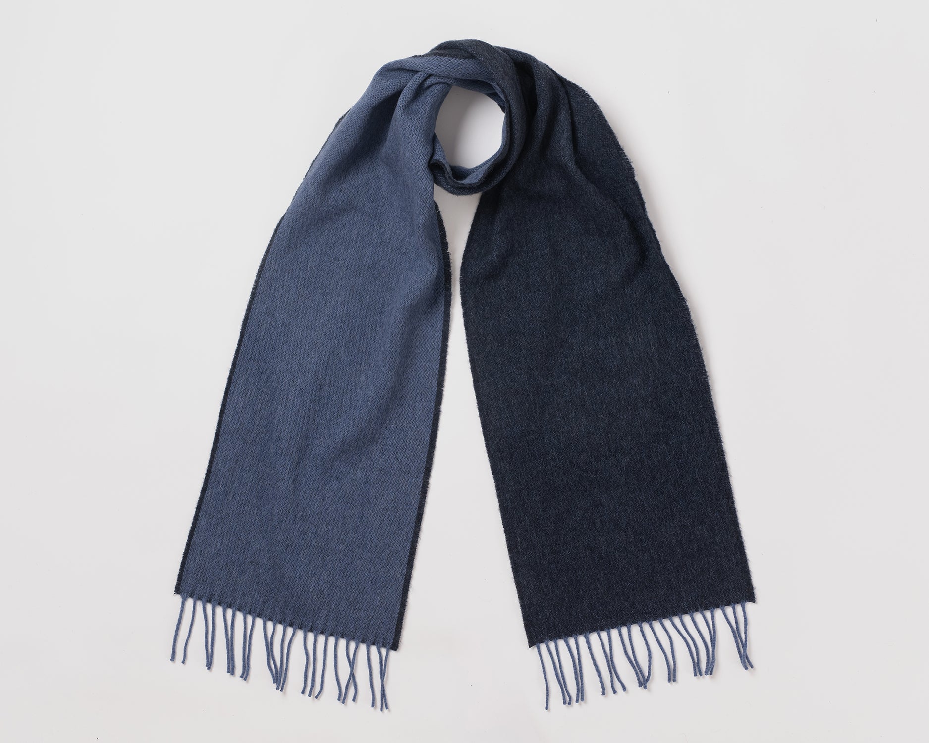 MacN dual reversible scarf in navy and denum Blue scarf with fringes on a light gray background